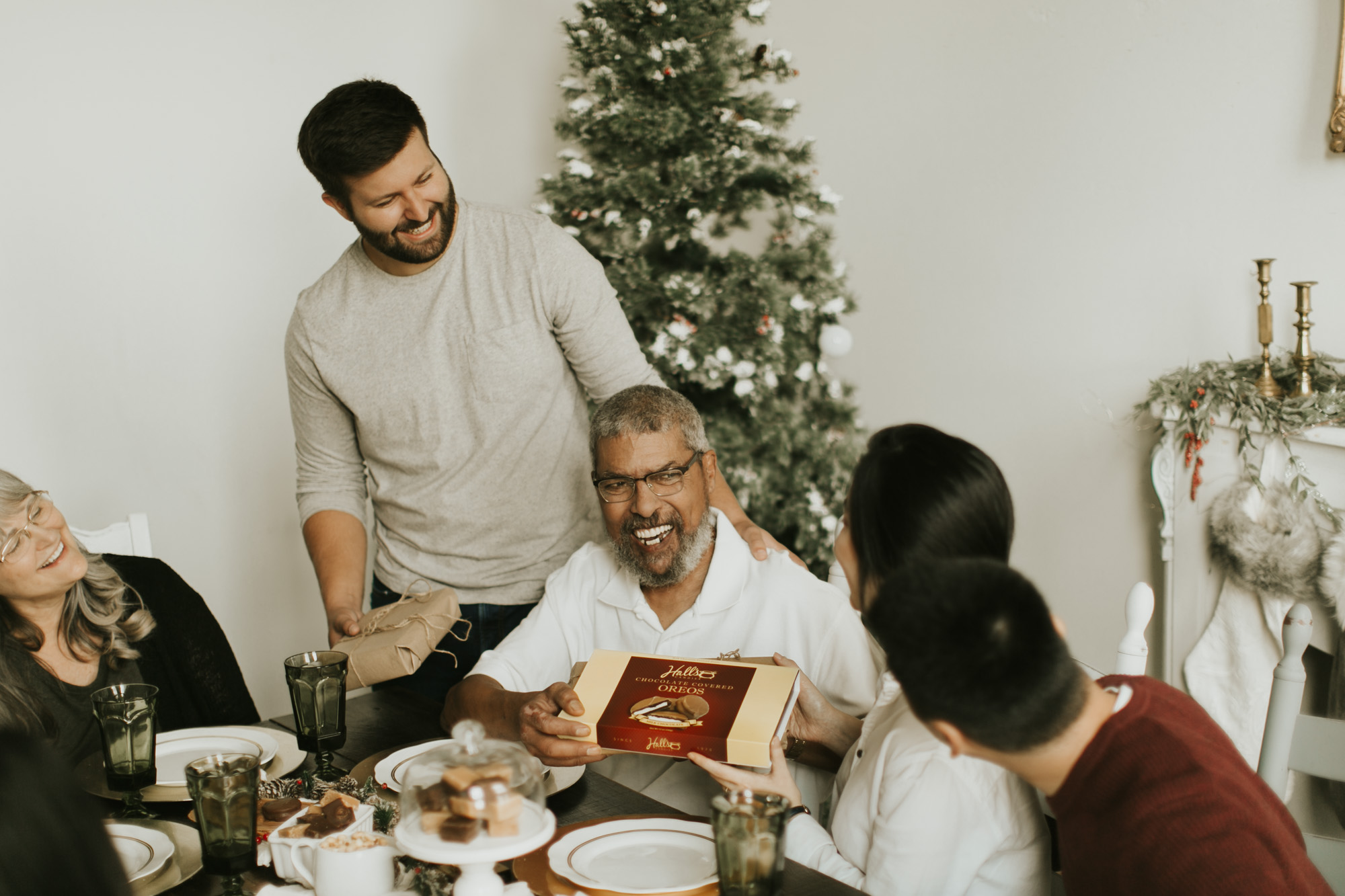 family laughing at dinner table and sharing Hall's chocolates